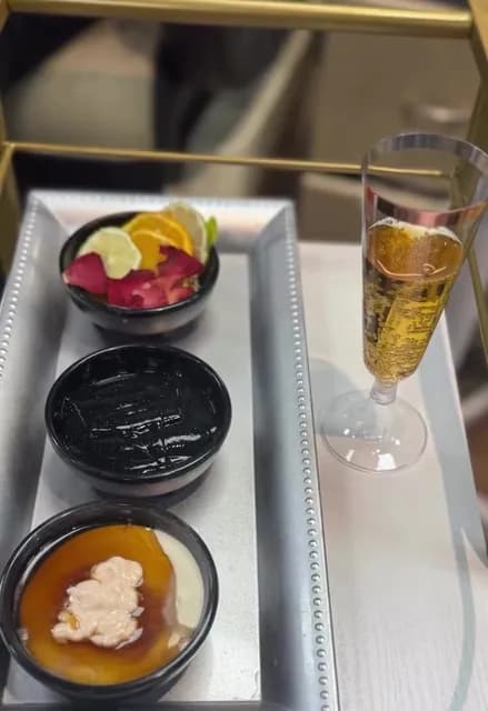 Deluxe pedicure tray with a fruit and petal soak, mask and scrub beside a glass of champagne