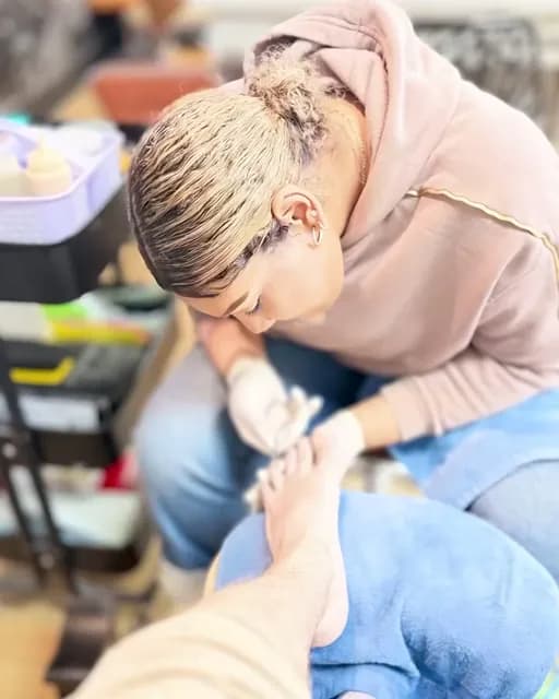Nail tech bent over a client’s pedicure at the spa chairs