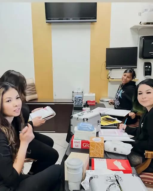 Academy instructors and students gathered around a table of lash kits