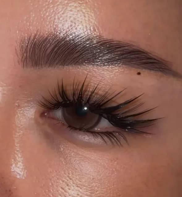 Close-up of a brown eye with a customized spiky lash set and a full brushed-up brow