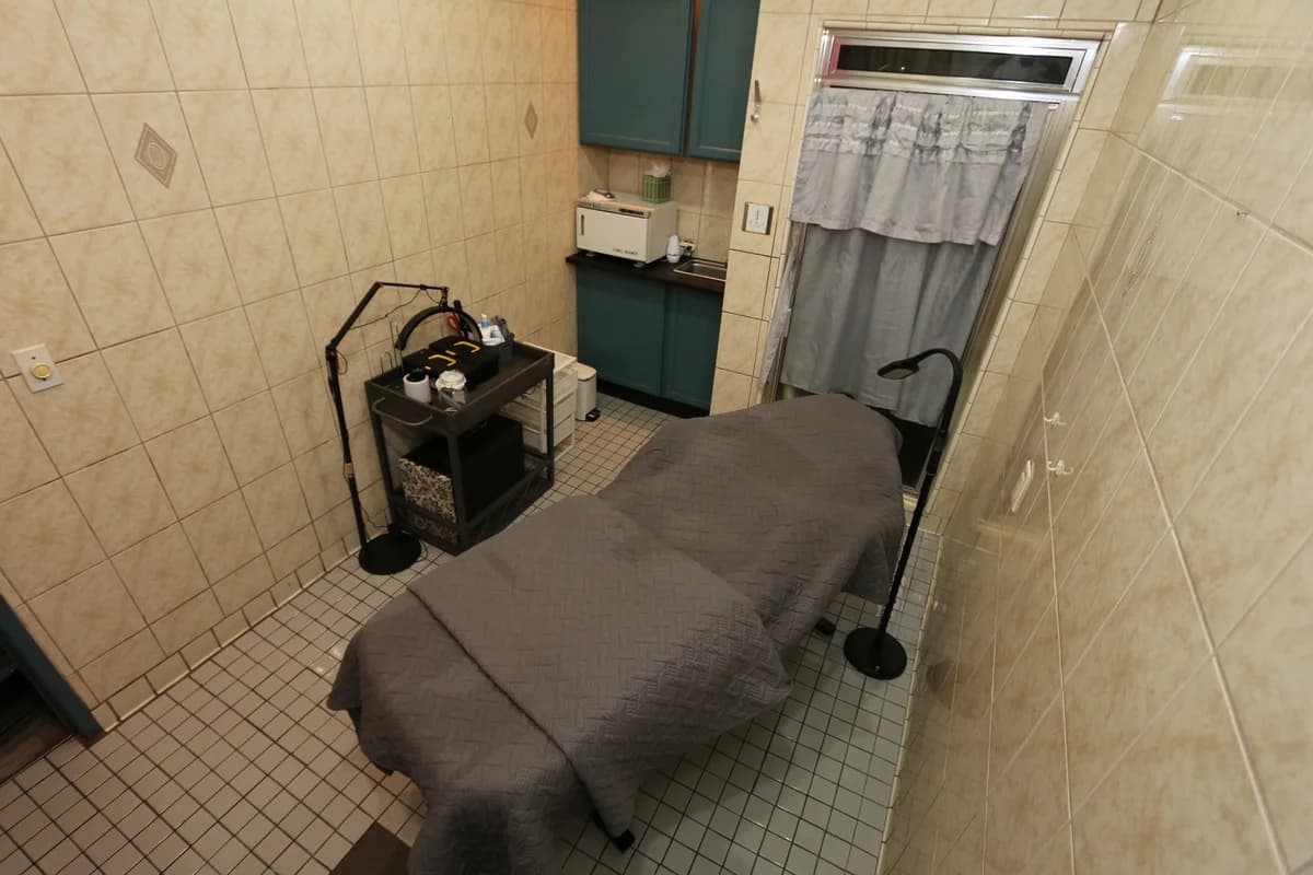 Tiled treatment room with massage bed.